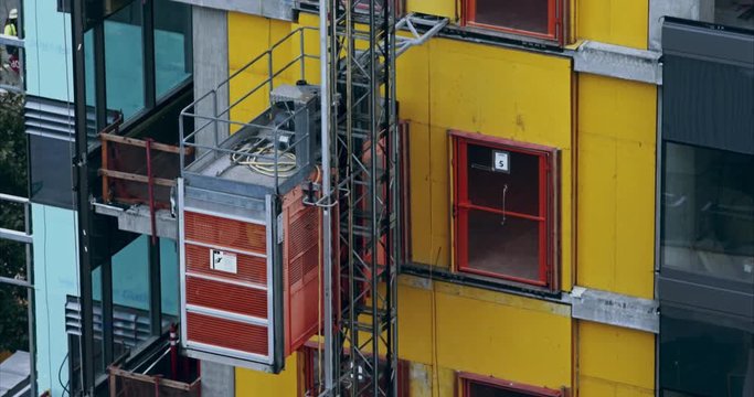 Construction elevator hoist moving up the outside of an unfinished building 4k