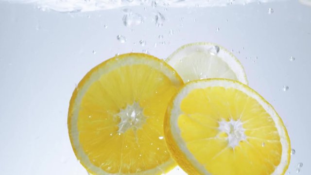 Close up shot of lemon slices falling into water