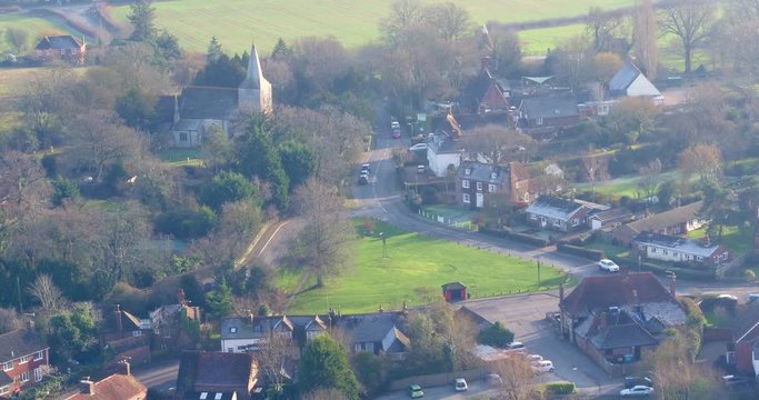 Wide aerial view of High Halden village, located in Kent (The Garden Of England) UK, with a pan up reveal of winters sun haze over the landscape.