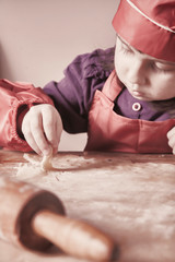  Cute little child girl chef making cooking homemade cakes. Food and сooking process concept.