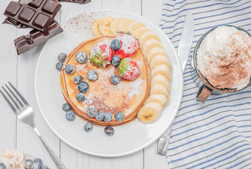Healthy breakfast, coffee and delicious homemade pancakes with fresh berries and banana