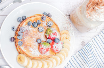 Healthy breakfast, coffee or cappuccino and homemade pancakes with fresh berries and banana