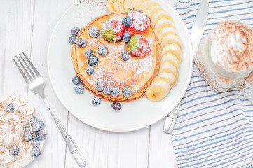 Healthy breakfast, coffee or cappuccino and homemade pancakes with fresh berries and banana