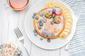 Healthy breakfast, black tea and homemade pancakes with fresh berries and banana