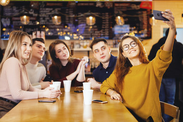 Five young handsome students sitting in a cafe.