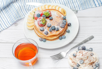 Healthy breakfast, black tea and homemade pancakes with fresh berries and banana