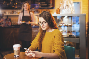 Young pretty woman and waitress in cafe.