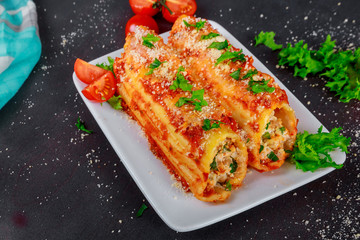 Manicotti on a plate with meat and tomato sauce and lettuce salad