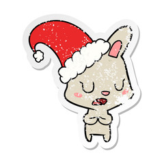 distressed sticker of a cartoon rabbit wearing christmas hat