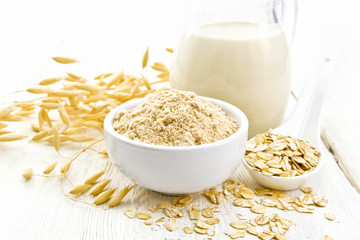 Flour oat in bowl with milk on light wooden board