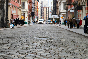 View of cobblestone covered Greene Street with bright sunlight background in the SoHo neighborhood...