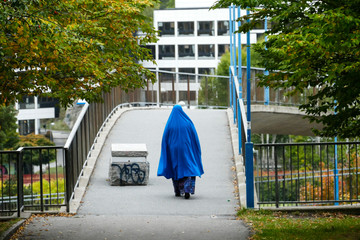 Stockholm, Sweden A Muslim woman in a blue veil walks on a pedestrian path.