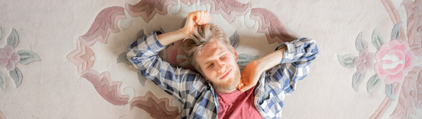 young man in shirt lay on the carpet and relax after busy day b