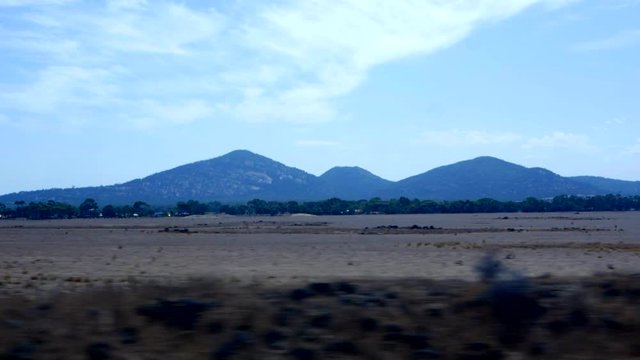 Looking out the window of a moving train. You Yangs mountain range in the distance as the train speeds along the rail tracks. SLOW MOTION.