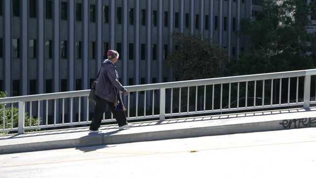 Old homeless woman walks downtown.
