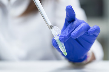 Scientist with pipette and test tube, examining samples and liquid in laboratory