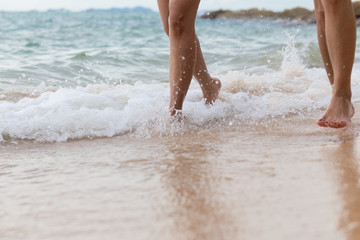 Fototapeta na wymiar The leg running on the beach with sea waves softly.