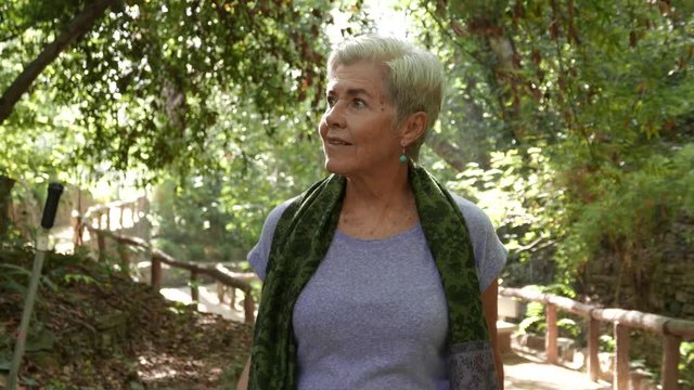 Older woman strolls through a park with a look of wonder and happiness.