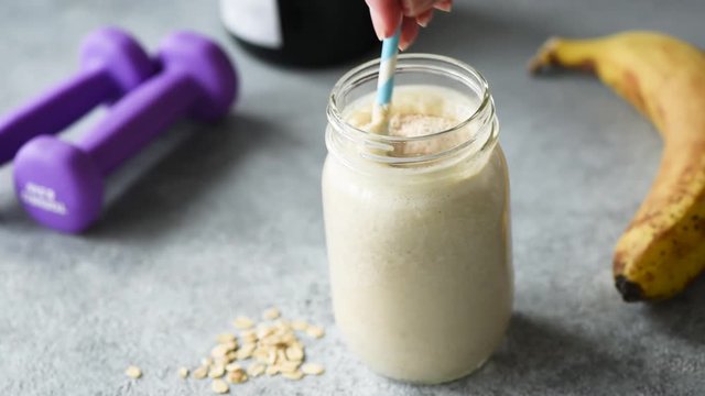Adding protein powder into smoothie. Woman adding scoop of protein powder into breakfast smoothie. Sporty healthy lifestyle concept