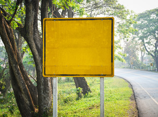 Yellow old blank road sign empty on the roadside with tree background