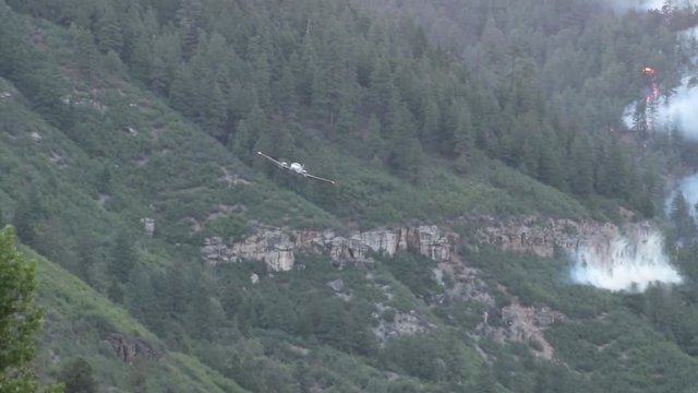 Fire spotter plane marking where to drop slurry for fire bomber at low altitude.
