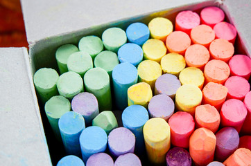 Colorful chalk in box for drawing on chalkboard on top view