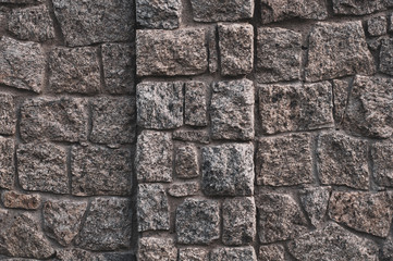 Old darkened from time to time wall with rough granite stones