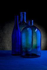 Still life with three glass bottles on a dark background