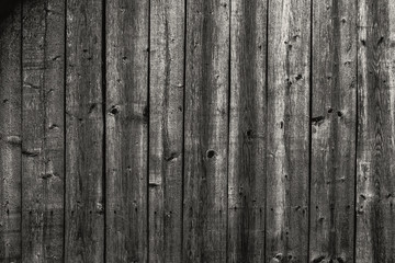 A wall made of old, darkened, frayed gray wooden knotty planks