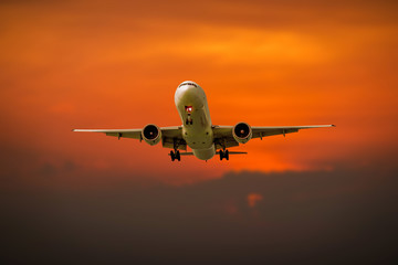 Passenger plane in flight. Aircraft fly high in the sky above the clouds during sunset on vacation during a journey . Front view of airplane.