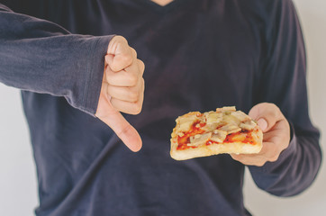 Young man rejecting pizza or unhealthy food showing thumbs Down. Dieting or good health concept. Unhealthy Eating Concept.