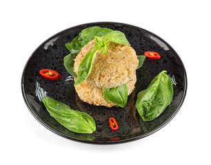 Steamed chicken patties in breaded, served with spinach leaves on a black plate, isolated on a white background with shadows. Dietary food. Top wiev.
