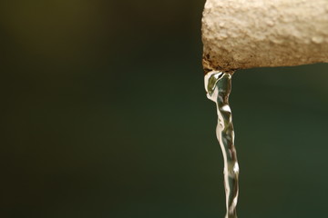 Close up of water pouring out of a pipe with space for text on the left.