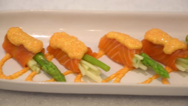 Juicy delicious salmon rolls meal arranged on a white platter plate, sliding shot