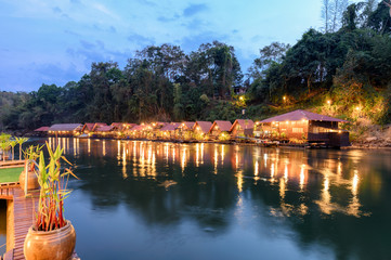 Tropical wooden raft resort illumination on river kwai at dawn