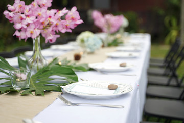 Dining set on the white table sheet with beautiful bouquet flower outdoor