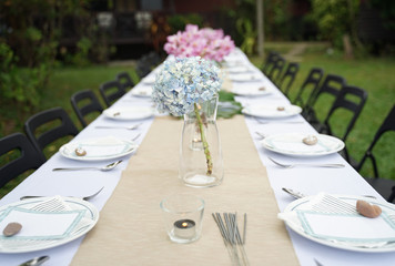 Dining set on the white table sheet with beautiful bouquet flower outdoor