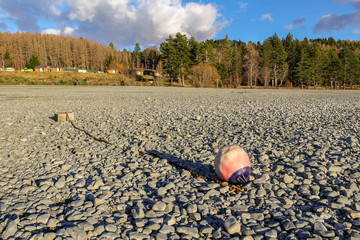 A buoy resting on the dry stones of a lake bed