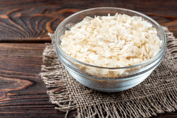 Rice flakes on dark wooden background.