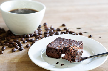 Brownie cake in white dish and black coffee on wooden table