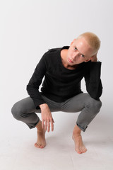 Full body shot of young handsome androgynous man crouching