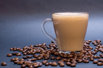 Transparent glass cup with coffee and coffee beans on blue background. Bright tone, soft focus