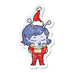 distressed sticker cartoon of a alien girl wearing santa hat