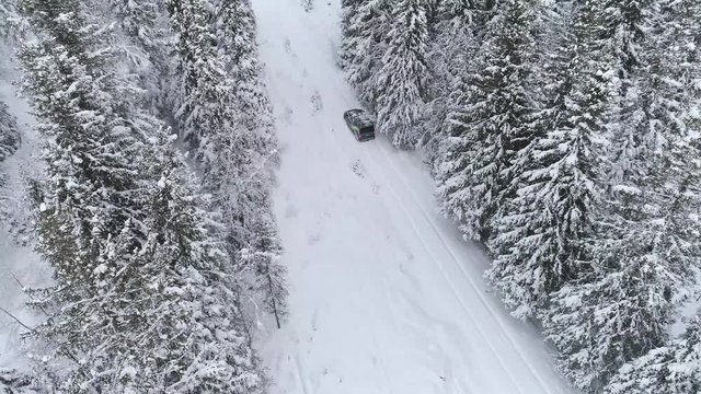 4k drone footage of car driving through snow in Norwegian forest.