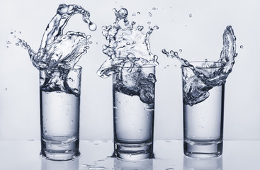 Three glasses with splashing water. Splashing water. Water out.