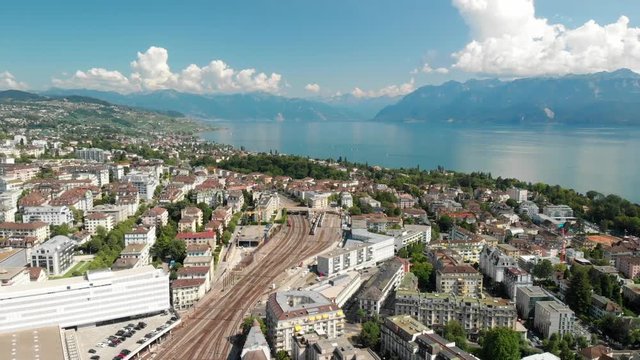 Beautiful aerial drone shot flying backwards above the train station of Lausanne Switzerland with lake Geneva in the background