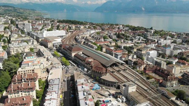 Beautiful aerial drone shot tilting down and flying towards the train station of Lausanne Switzerland with lake Geneva in the background