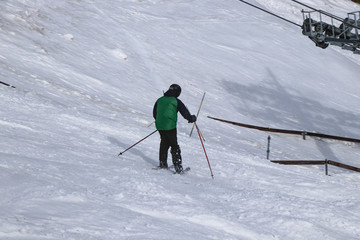 Fototapeta na wymiar Old man skiing in free ride. Granpa carve on skis. Green jacket. A man transfers weight from one foot to the second.