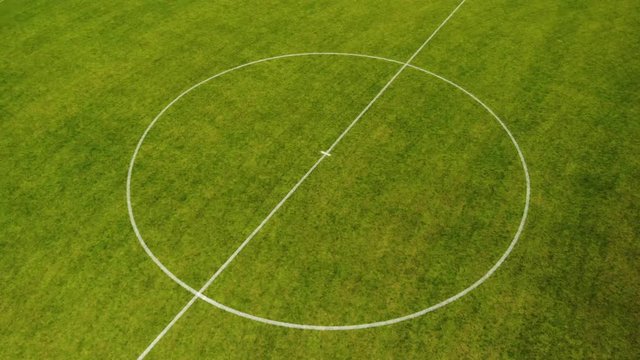 Aerial drone shot circling around center circle of football field long