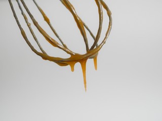 Whisk with caramel isolated on white background